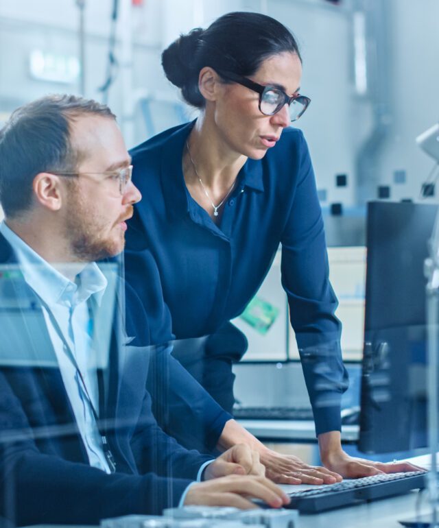 modern-electronics-factory-female-supervisor-talks-male-electrical-engineer-who-works-computer-with-cad-software-developing-pcb-microchips-semiconductors-telecommunications-equipment